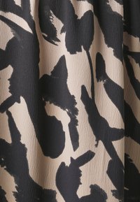 Textured fabric in beige with black abstract brushstroke pattern, featuring a wavy surface and varying shapes throughout the design.