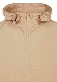 Beige letvægtsjakke med halv-zip lukning, justerbar snorehætte og glat tekstur. Har minimal syning og et enkelt design.