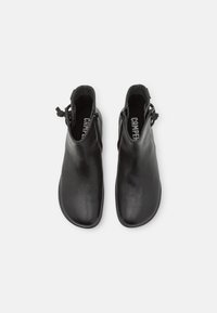 Black leather ankle boots featuring a smooth texture, rounded toe, and a zip closure on the side. Brand name is visible inside.
