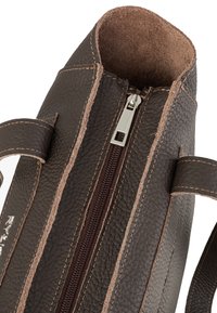 Sac à main en cuir marron avec surface texturée, fermeture éclair et coutures contrastantes de couleur marron clair. Il dispose de deux poignées pour le transport.