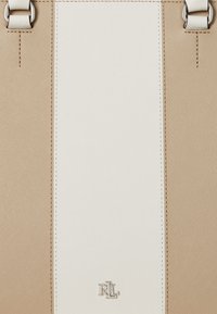 Beige and white handbag featuring a textured finish, prominent stitching, metallic hardware, and a small silver logo at the base.