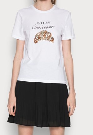 Witte katoenen t-shirt met zwarte tekst "BUT FIRST" boven een pailletten croissant graphic. Ronde halslijn en korte mouwen.