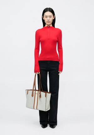 Top rojo de manga larga con ribete, con cuello alto, combinado con pantalones acampanados negros y un bolso tote beige con estampado y detalles marrones.
