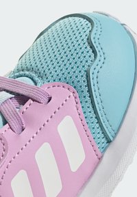 Niebieska, siateczkowa cholewka z różowymi syntetycznymi nałożeniami. Z białymi akcentami i fioletowymi sznurowadłami. Zaokrąglony nosek z teksturowanym wykończeniem.