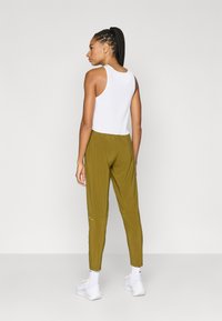 Λευκό ριμπ αμάνικο τοπ συνδυασμένο με χακί, στενά παντελόνια jogger με κωνικό κόψιμο. Τα παντελόνια διαθέτουν ελαστική μέση και μανσέτες στους αστραγάλους. Λευκά αθλητικά παπούτσια ολοκληρώνουν την εμφάνιση.