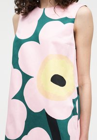 Αμάνικο φόρεμα με μεγάλο αφηρημένο λουλουδάτο σχέδιο σε ροζ, κίτρινο, μαύρο και σκούρο πράσινο χρώμα σε υφάσμα ανοιχτό ροζ.