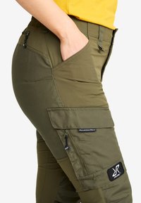 Olivgröna cargobyxor med hög midja, sidofickor och en lapp med "RevolutionRace". Tillverkade av tåligt och flexibelt material.