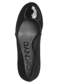 Černá patentní kůže a semišová pumpa se zaoblenou špičkou, zakřiveným siluetou a výrazným logem DKNYC na stélce.