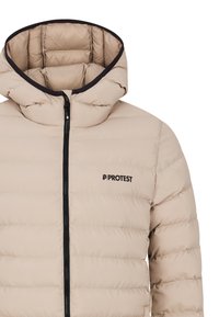 Doudoune beige avec capuche, fabriquée en tissu matelassé. Présente une fermeture éclair noire et un logo sur la poitrine. Texture lisse et design léger.