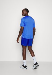 Camiseta deportiva azul de manga corta, combinada con pantalones cortos azules a juego. La tela tiene una textura suave, diseñada para ropa deportiva.