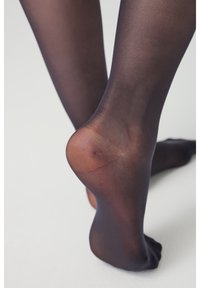 Durchsichtige schwarze Strumpfhosen mit glatter Textur und einer auffälligen Rückennaht, die den Fersen- und Knöchelbereich betont.