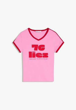 Rózsaszín V-nyakú póló piros szegéllyel az ujjain és a gallérnál, vastag piros felirattal: "76 hazugság" és alatta kisebb, dőlt motivációs szövegek.