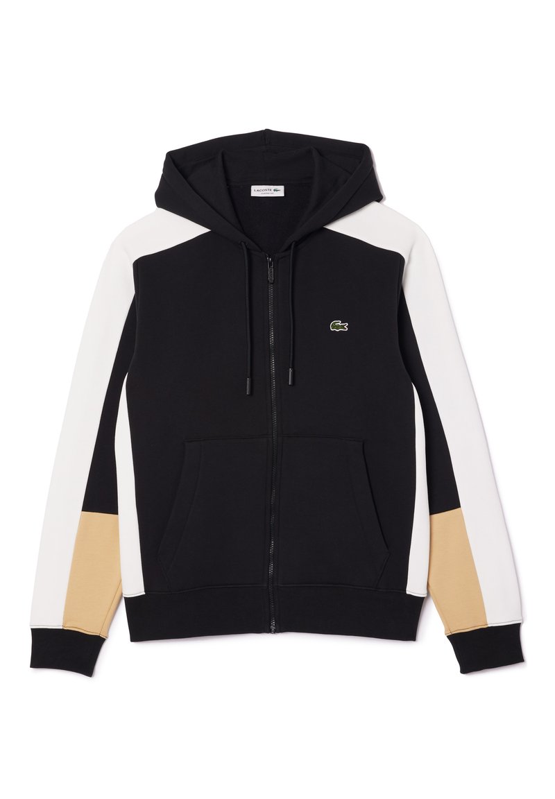 Haut à capuche zippé noir avec des panneaux latéraux contrastants blancs et beiges, une poche kangourou et un petit logo vert sur la poitrine.