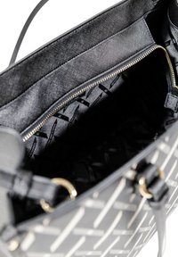 Borsa nera con un motivo geometrico, caratterizzata da un esterno in tessuto testurizzato, zip dorata e fodera liscia con stampa del logo.