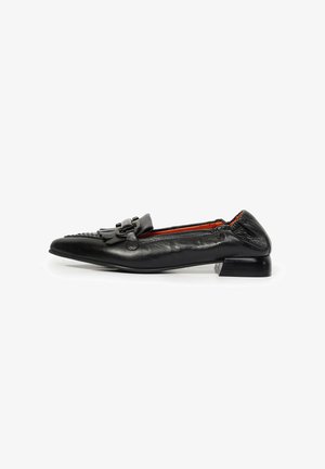 Mocasín de cuero negro con tacón bajo, detalle de flecos y una hebilla decorativa en la parte superior, mostrado de lado sobre un fondo blanco.