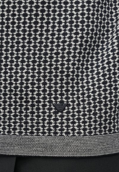 Melns un balts auduma raksts ar suņu ziloņu rakstu un pelēku ribota apakšmalu. Mazs logotipa elements apakšējā centrā. Mīksta tekstūra.