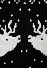 Maglione lavorato a maglia nera con un motivo di renne bianche, con motivi ripetuti e fiocchi di neve bianchi sparsi.