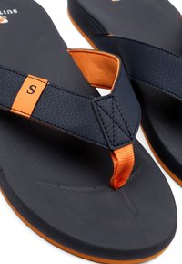 Zwarte slippers met getextureerde marineblauwe banden, oranje accenten en een contourede zool. Voorzien van een klein logo en een zachte voetbed voor comfort.