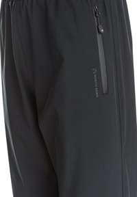 Sorte sportsbukser lavet af glat stof. Har en lynlåslomme og et logo på siden. Elastisk talje for komfort.