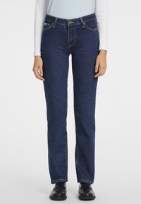 Jeans de pierna recta azul oscuro, hechos de denim con una textura lisa, que cuentan con cinco bolsillos y costuras doradas a lo largo de las costuras.