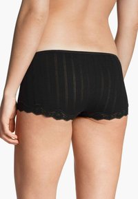 Zwarte boyshorts met kantaccenten, gemaakt van zachte, gestructureerde stof met verticale strepen. Scalloped kant langs de zoom voegt detail toe.