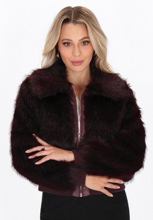 Burgundy faux furjakke med lynlås foran, cropped design og ribbede manchetter. Blød tekstur og pelsdetaljer omkring kraven og ærmerne.