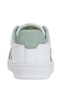 Sneaker bianco con una linguetta sul tallone in verde menta testurizzato, accenti laterali a motivo e una suola in gomma. Presenta materiali lisci e testurizzati.