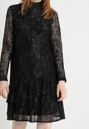 Schwarzes Spitzenkleid mit langen Ärmeln, hohem Kragen und gestuftem Rüschensaum. Blumenmuster im gesamten Kleid und semi-transparente Textur.