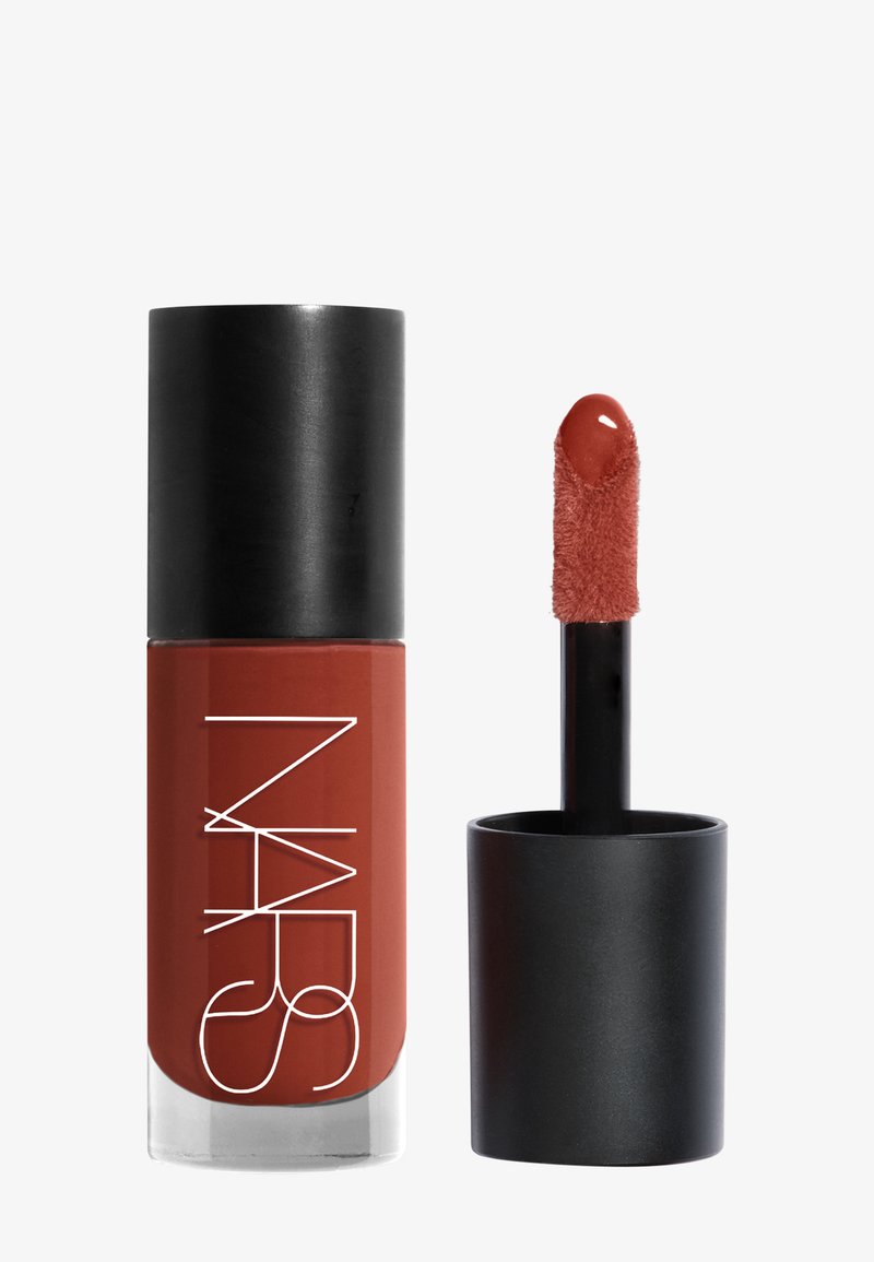 Rouge à lèvres liquide mat dans une teinte terre cuite chaude avec un capuchon noir, de la marque NARS, et un applicateur en forme de doe-foot recouvert de produit.