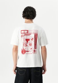Witte korte mouwen t-shirt met een rode grafische illustratie op de achterkant, die een straatbeeld van Tokio weergeeft met tekstaccenten.