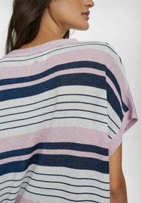 Svītrots džemperis rozā, tumši zilā un baltā krāsā. Izgatavots no teksturēta adījuma auduma ar īsām piedurknēm un pogu detaļu aizmugurē.