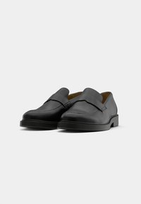 Sorte skinnloafers med flat hæl, jevn tekstur, enkelt design og bred stropp over vristen for sikker passform.