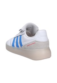 Baskets blanches avec des rayures bleues, talon en daim beige, texte rouge "Barreda Mundial" et semelle épaisse translucide, vues de l'arrière.