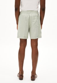 Lichtgroene shorts van een textuur stof met een elastische tailleband en zijzakken, met een opgerolde zoom en achterkant zakdetail.