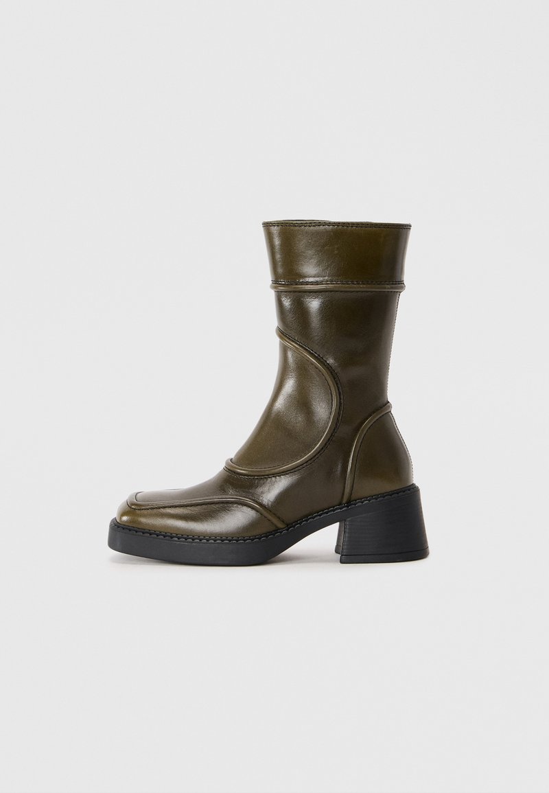 Oliivivihreät nahka nilkkurit, joissa on pyöreä kärki, joustava paneeli ja paksu musta korko. Sujuva rakenne ja hienovaraiset ompeluyksityiskohdat.