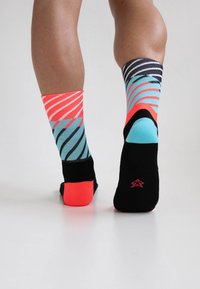 Bunte Socken mit auffälligen Mustern in Pink, Blau und Schwarz. Gestreiftes Design mit kontrastierenden Zehen- und Fersenabschnitten, die mehrere Farben zeigen.