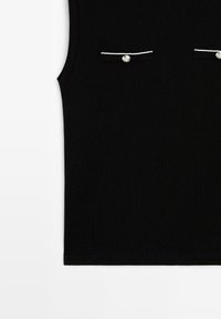 Black sleeveless top made of soft fabric, featuring two chest pockets with white stitching and silver buttons for accent.