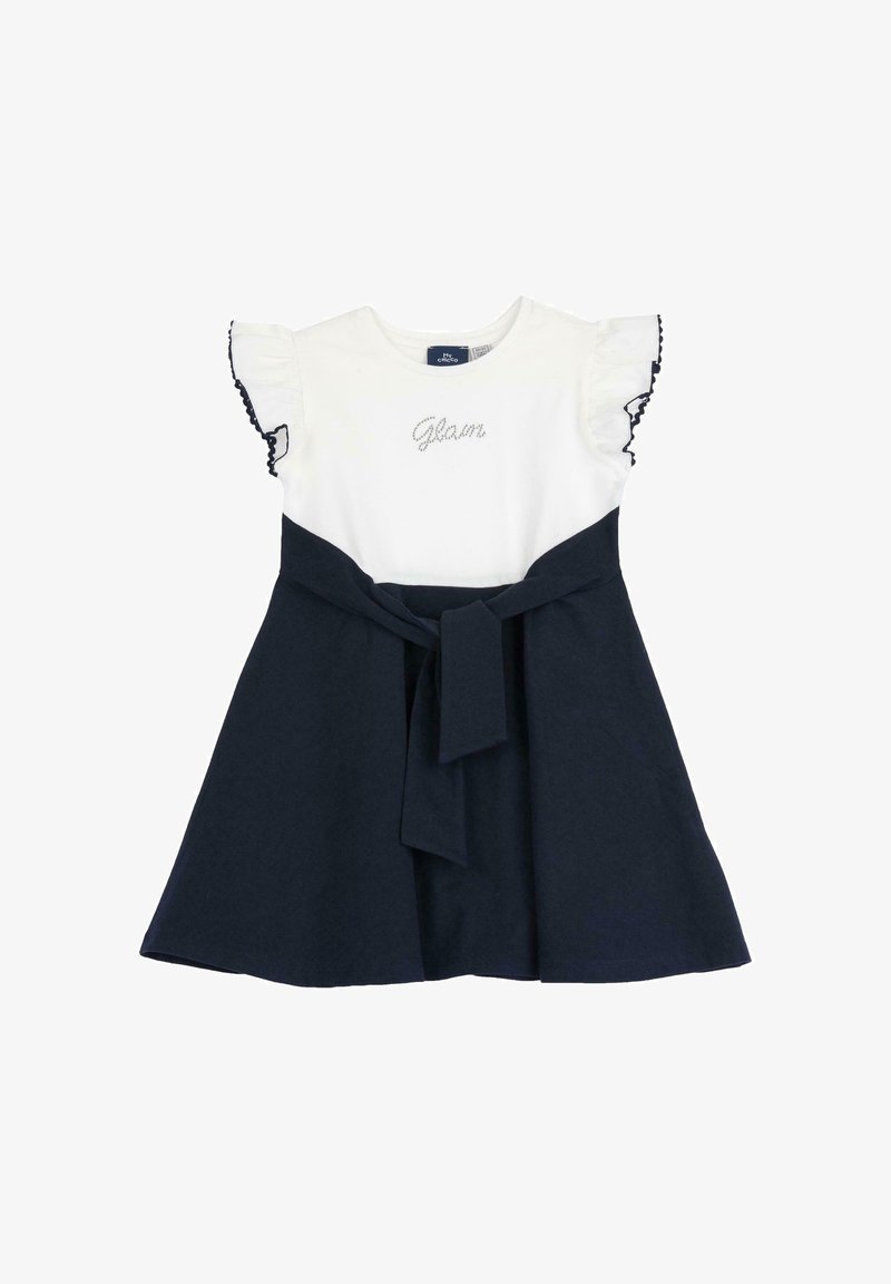 Robe blanche et marine à manches courtes avec manches volantées, texte « Glam » en strass sur le corsage blanc, et un nœud de ceinture marine.