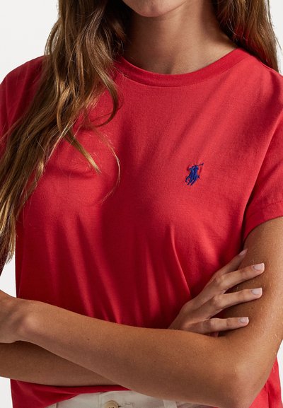 T-shirt rossa in cotone con maniche corte, scollo rotondo e piccolo logo ricamato blu sul petto sinistro. Tessuto morbido e vestibilità rilassata.