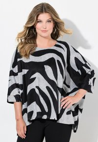 Černá a šedá oversized blůza se zebra vzorem, vyrobená z měkkého, texturovaného materiálu. Má kulatý výstřih a široké rukávy.