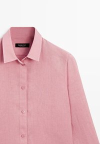 Rosa Leinenhemd mit langen Ärmeln, spitzem Kragen und Knöpfen vorne, zeigt den oberen Rumpfbereich vor weißem Hintergrund.