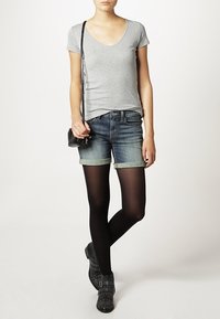 Harmaa lyhythihainen paita, siniset farkkushortsit, joissa käänteet, mustat leggingsit ja mustat niittikengät nilkkamittana. Pieni olkalaukku.