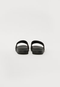 Black rubber slide sandals with flat soles, open toe, and dual strap design, featuring a smooth texture and minimalist style.