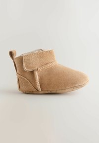 Stivaletto beige in suede con foderatura morbida, punta curva, cinturino regolabile con velcro e suola testurizzata per una presa migliore.