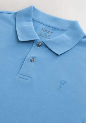 Polo shirt azzurro chiaro con lavorazione a maglia testurizzata, colletto con due bottoni, maniche corte e un piccolo dettaglio ricamato sul petto. Vestibilità regolare.