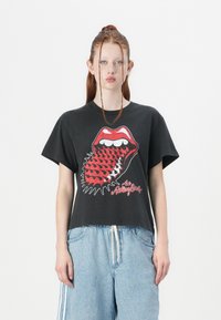 Black cotton t-shirt with a bold red and white Rolling Stones logo featuring a mouth with a tongue, short sleeves, and a relaxed fit.