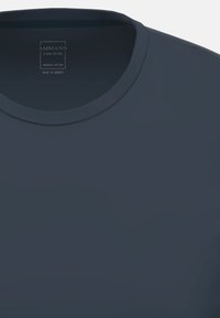 Mörkblå ekologisk bomull t-shirt med rund halsringning, detaljerad sömnad och en etikett som säger "AMMANN, nära dig, tillverkad i Europa."