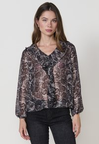 Blusa nera trasparente con motivo a serpente, colletto arricciato, maniche lunghe a sbuffo e vestibilità confortevole. Texture liscia e tessuto leggero.