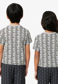 T-shirt grigio a maniche corte con un motivo geometrico nero, abbinato a pantaloni neri con motivo. Design casual con una vestibilità rilassata.