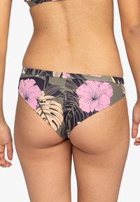 Vändbara bikiniunderdelar med en mörkgrön bas och rosa blommor samt bladmönster. Materialet verkar elastiskt och glatt.